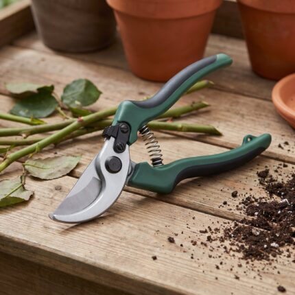 Fieldstone 8 inch bypass hand pruner on a wooden potting bench with cut rose stems