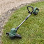 Trailhead string trimmer lying on the lawn, full length from head to battery