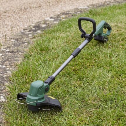 Trailhead string trimmer lying on the lawn, full length from head to battery